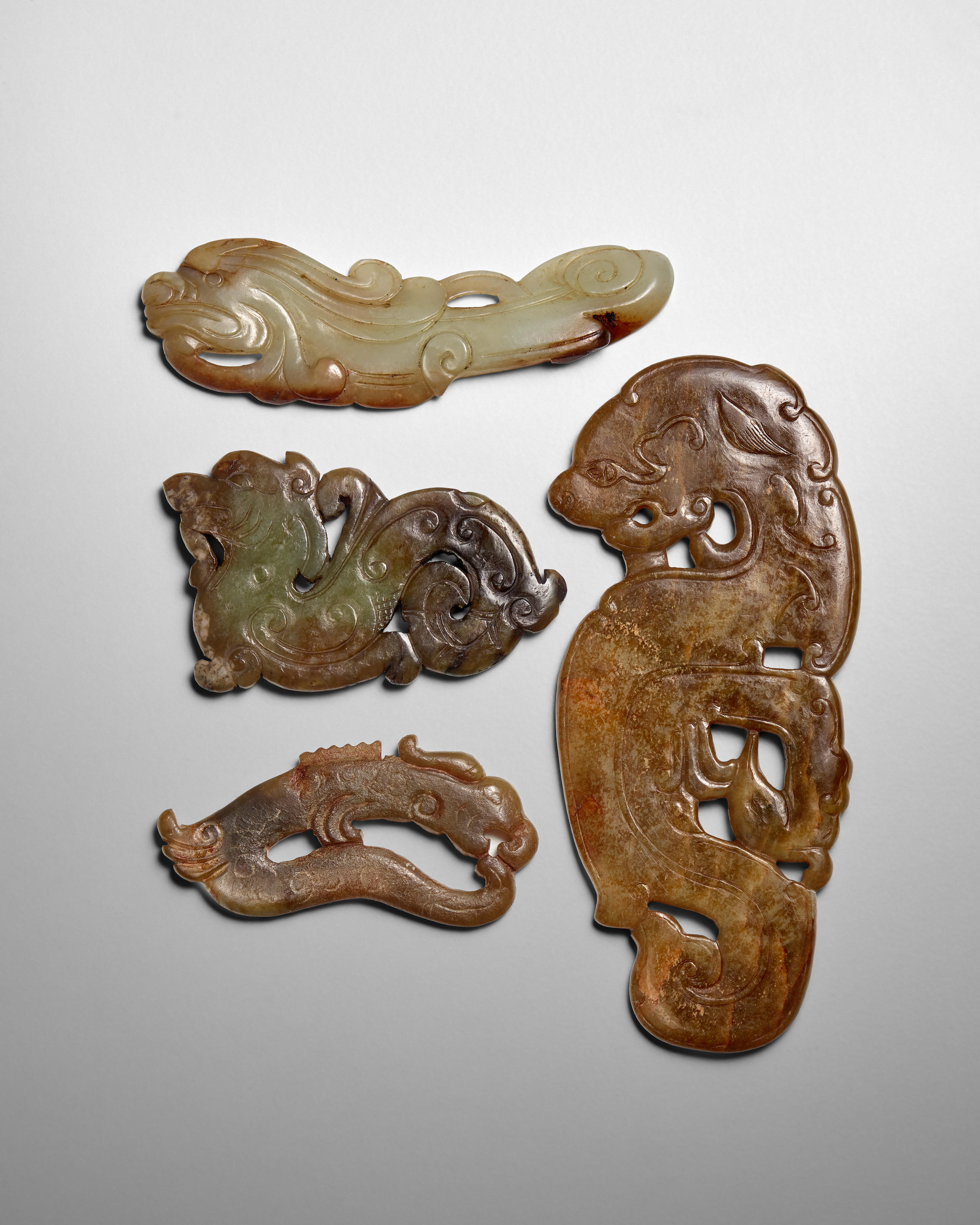 Appraisal: FOUR ARCHAISTIC JADE PLAQUES Late Qing Dynasty The olive-green recumbent