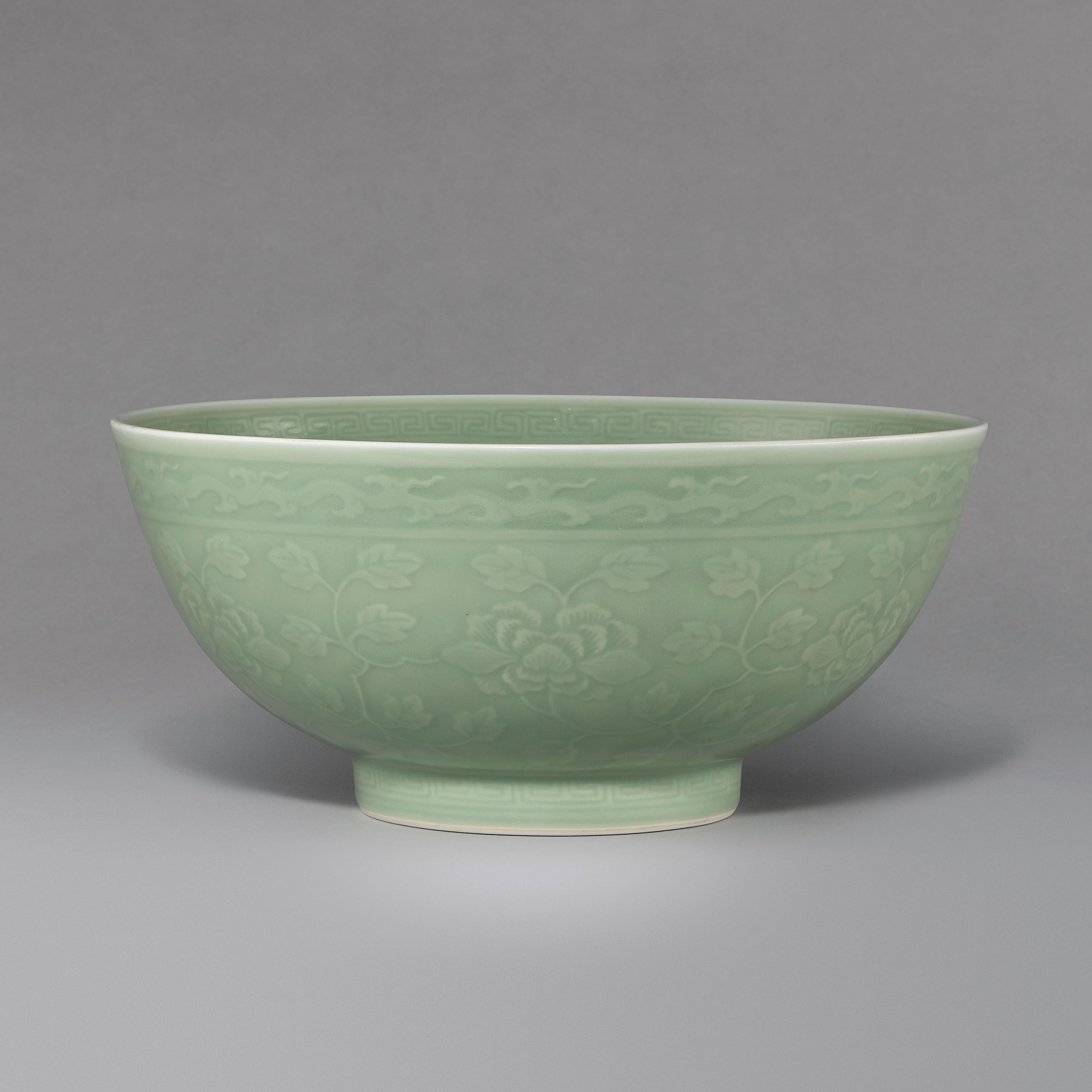 Appraisal: A LARGE CARVED AND MOULDED CELADON-GLAZED 'FLORAL' BOWL Qianlong seal