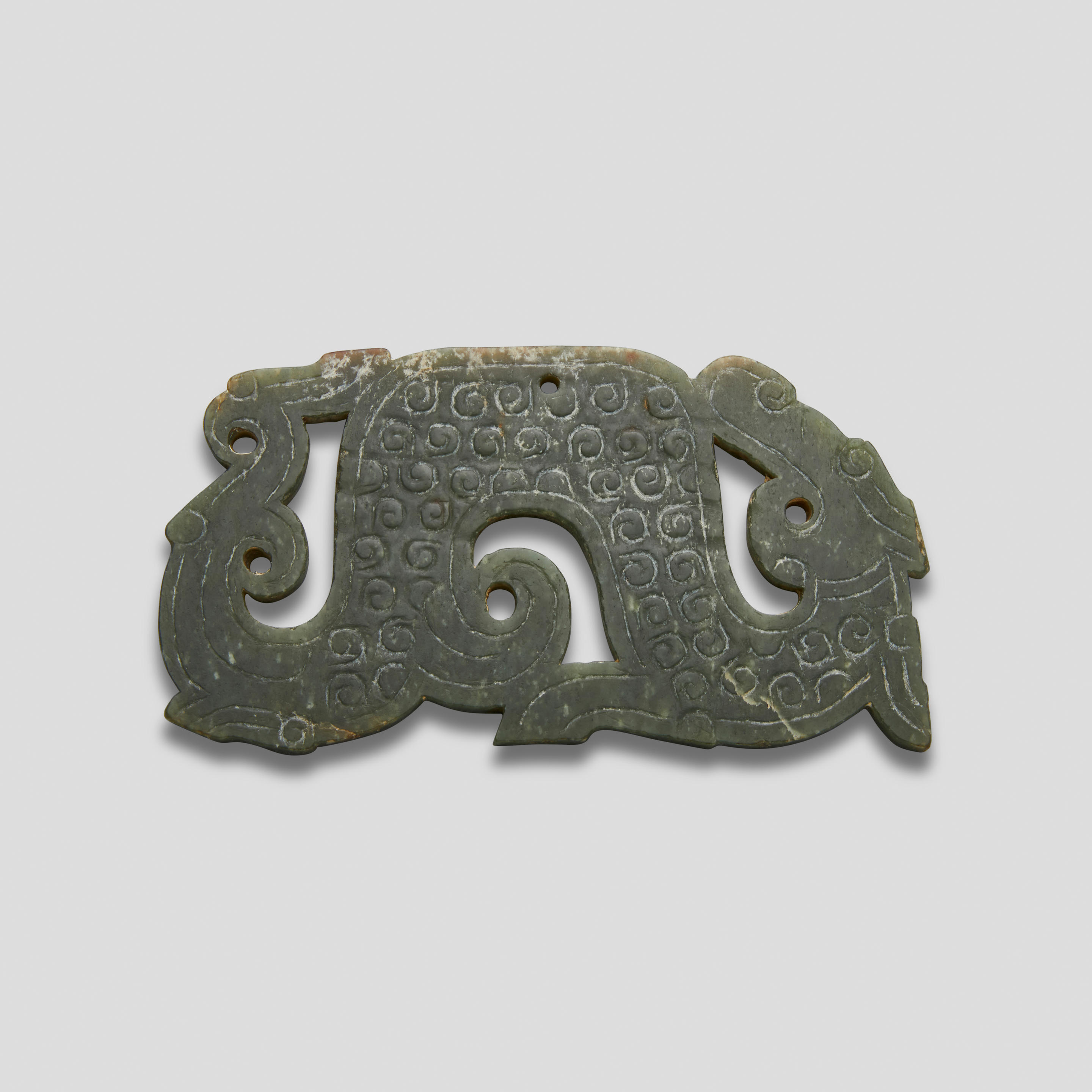 Appraisal: A GREEN JADE 'DRAGON' PENDANT Warring States period Worked in