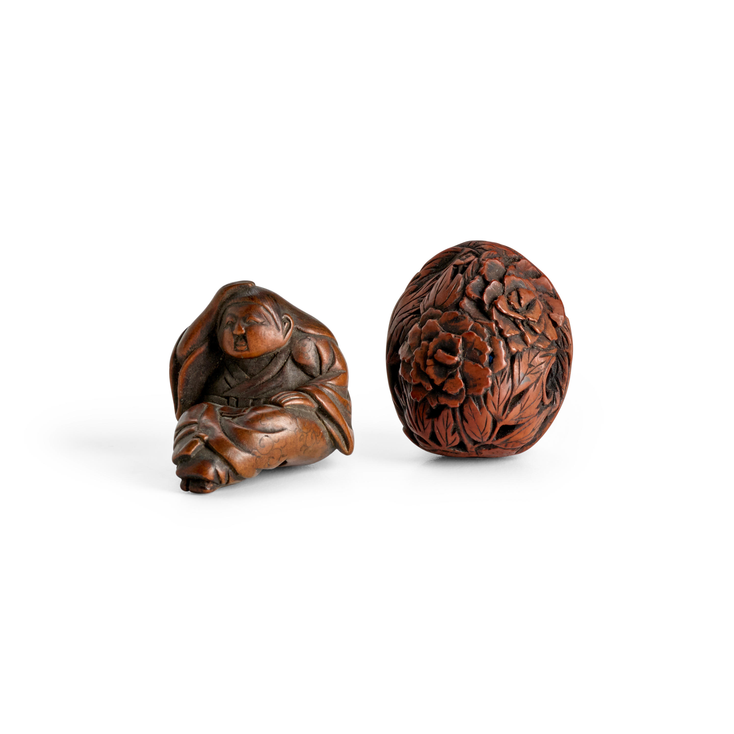 Appraisal: A WOOD NETSUKE AND A FRUIT NUT NETSUKE The first