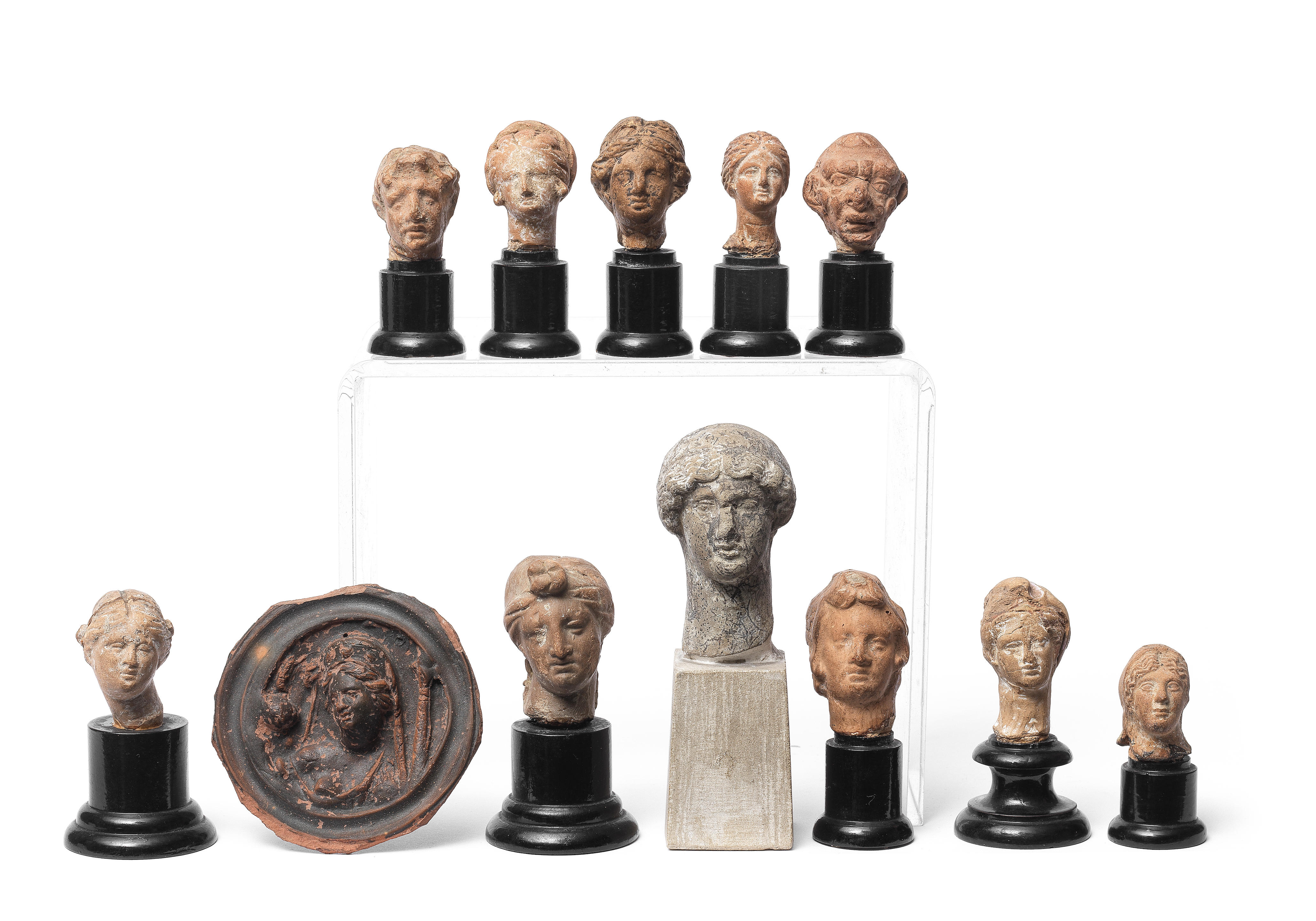 Appraisal: ELEVEN GREEK AND ROMAN TERRACOTTA HEADS AND A BLACK-GLAZED ROUNDEL