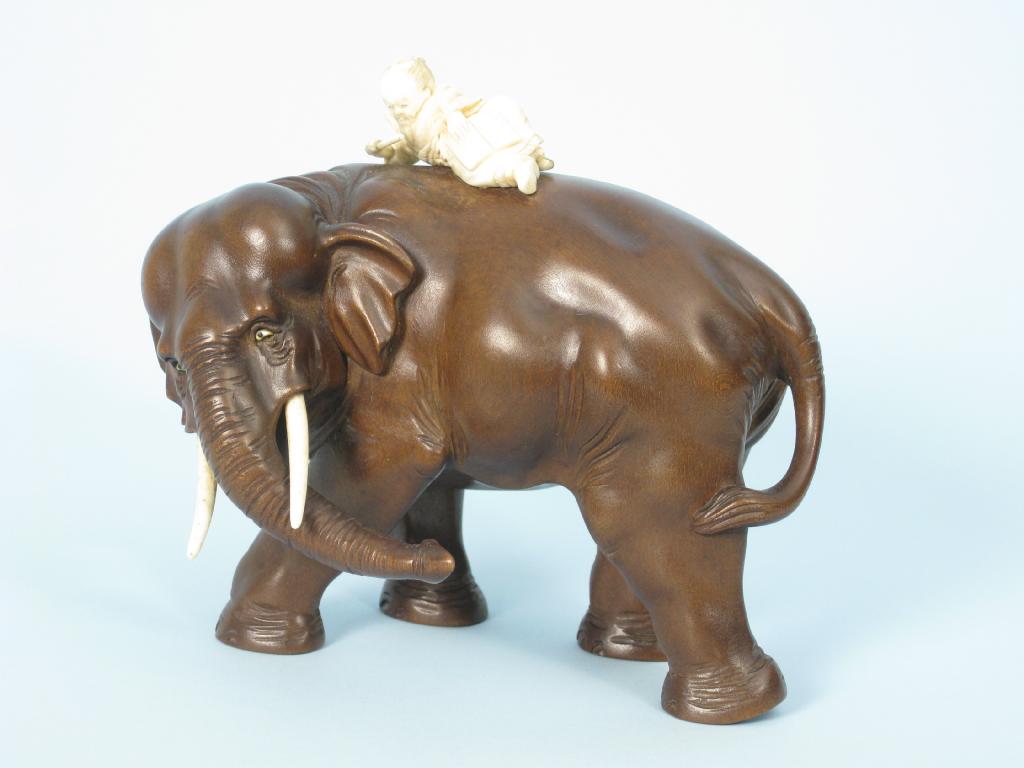 Appraisal: A Japanese carved hardwood Elephant surmounted by reclining ivory figure