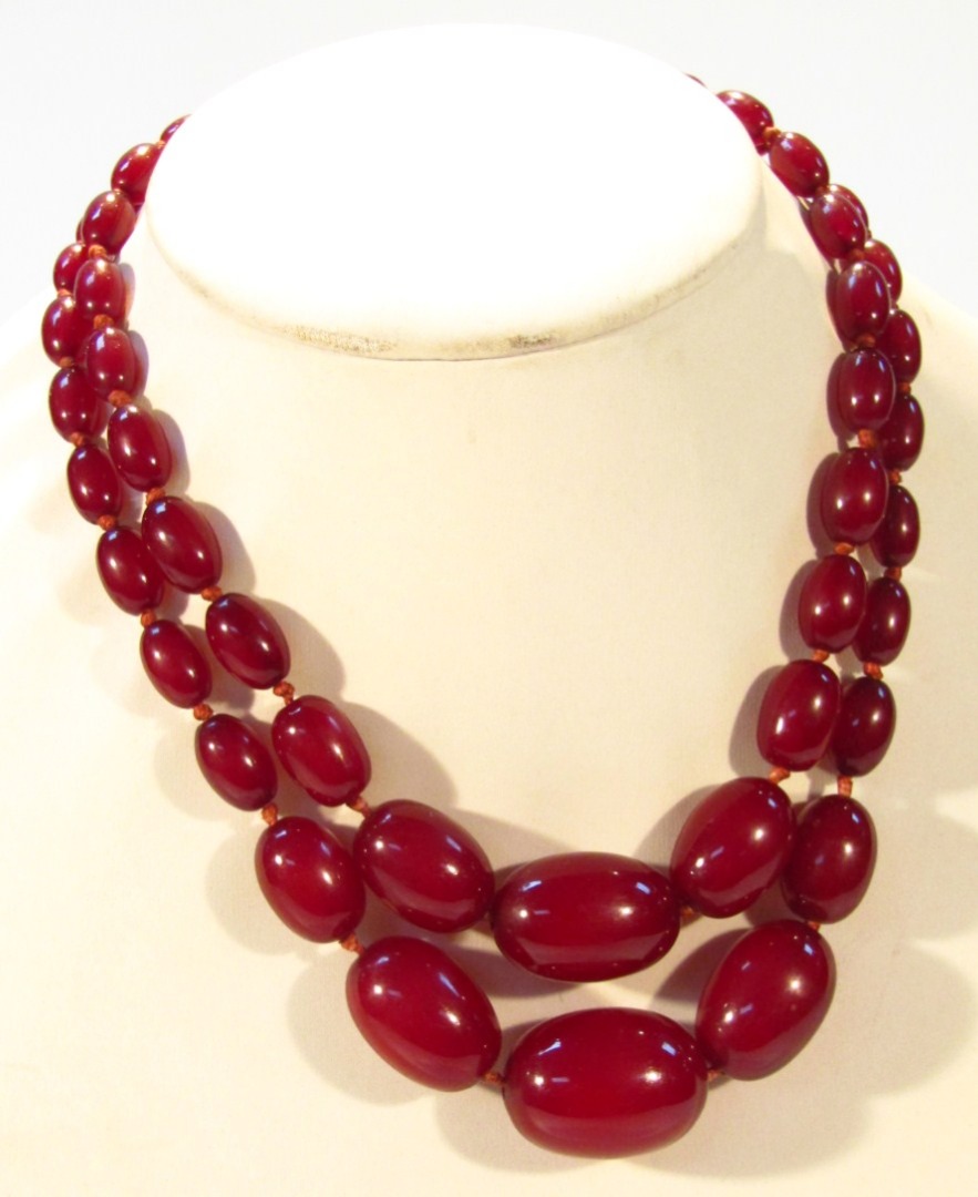 Appraisal: A string of red amber coloured beads each of oval