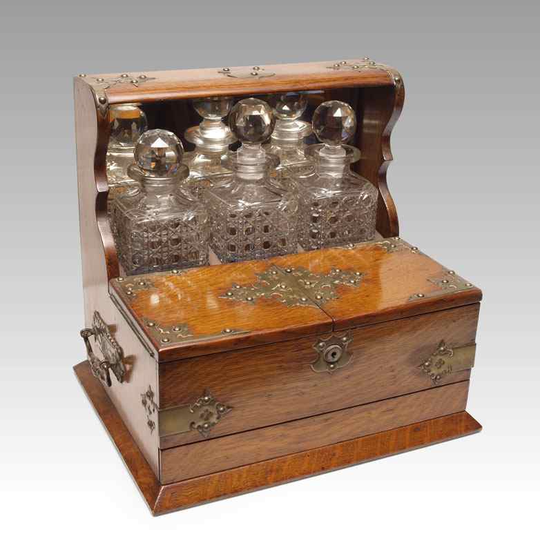 Appraisal: VICTORIAN OAK TANTALUS WITH BOTTLES Oak case with tacked brass