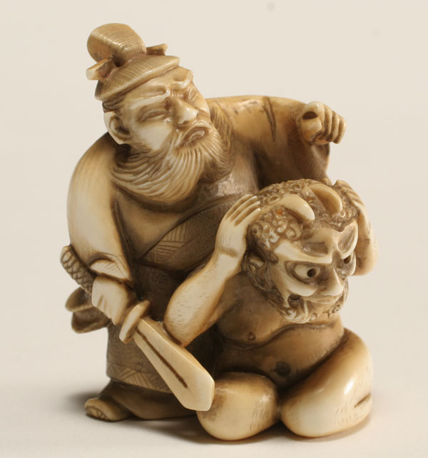 Appraisal: Japanese ivory netsuke armed standing male figure hovers menacingly over