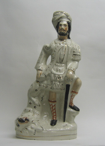 Appraisal: STAFFORDSHIRE POTTERY FIGURE GROUP Depicting Scottish hunter with lion on