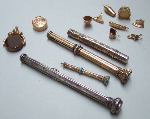 Appraisal: Eight gold charms including a drum and a wheelbarrow a