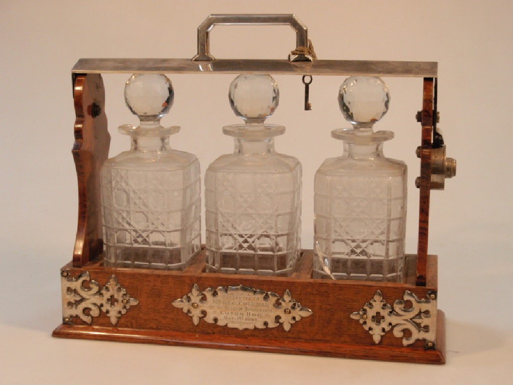 Appraisal: An Edwardian oak and electroplate three bottled Tantalus decanters AF