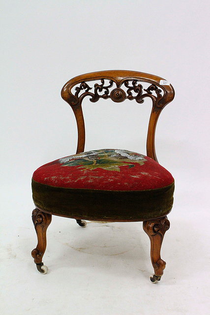 Appraisal: A VICTORIAN WALNUT LOW OCCASIONAL CHAIR with pierced scrolling acanthus