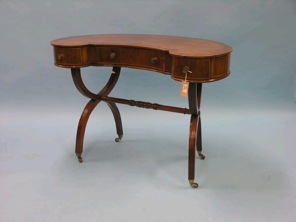 Appraisal: A mahogany kidney-shape writing table cross-banded top on X-shape underframe