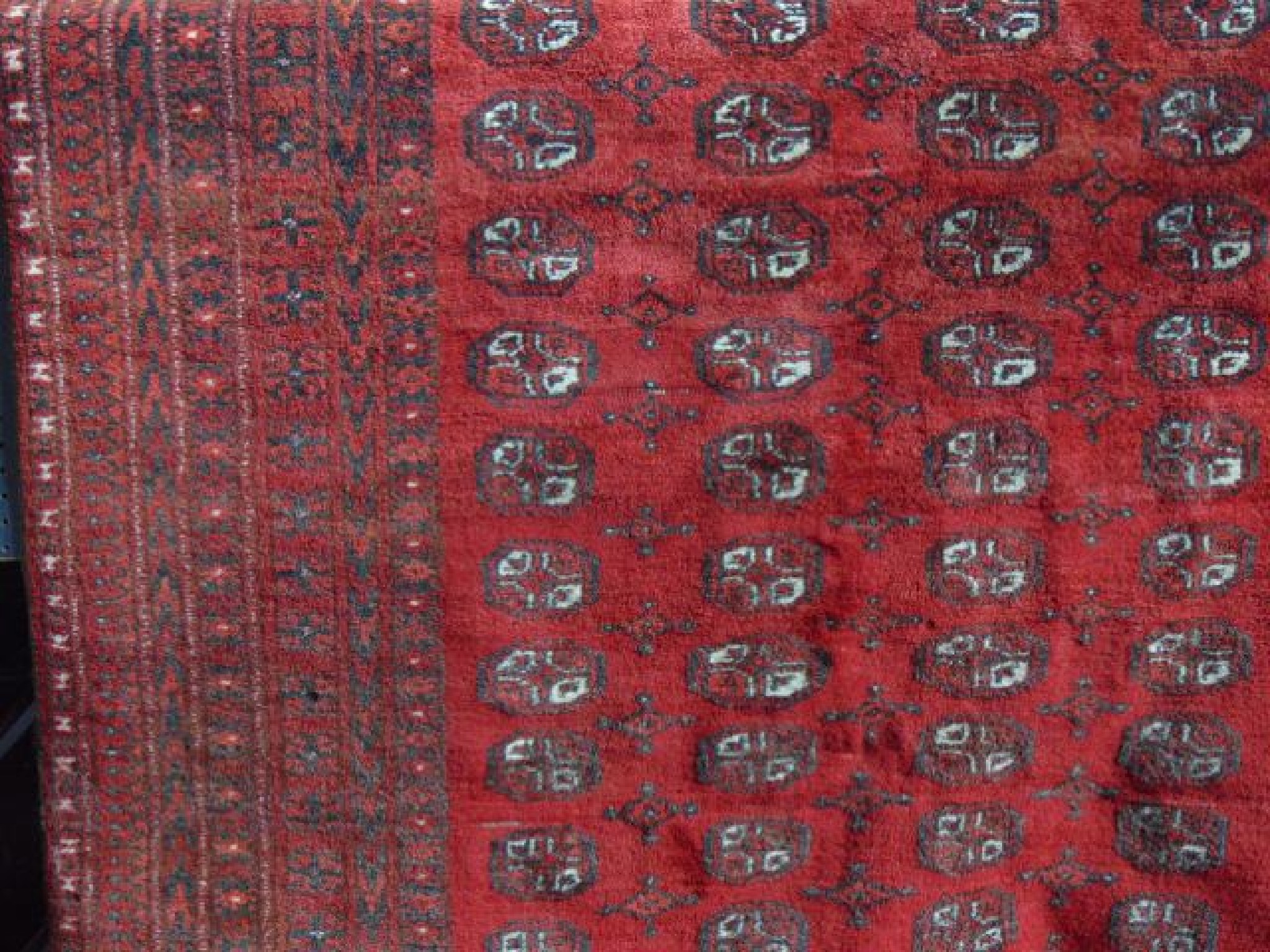 Appraisal: An Afghan red wool carpet with multi geometric detail within