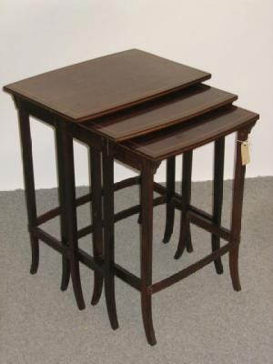 Appraisal: A NEST OF THREE EDWARDIAN MAHOGANY TABLES of bowed oblong