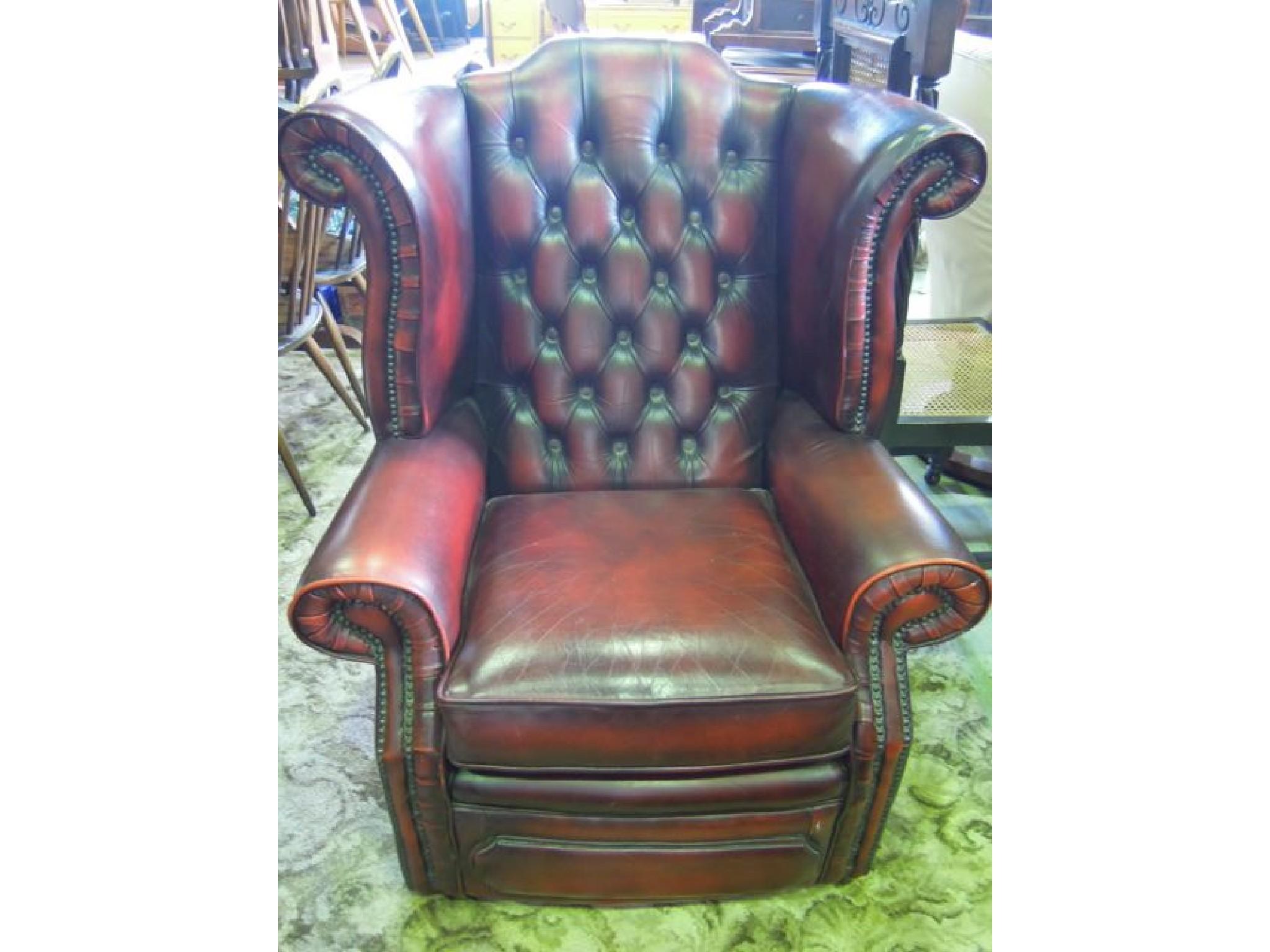 Appraisal: A maroon leather upholstered wing and button back armchair in