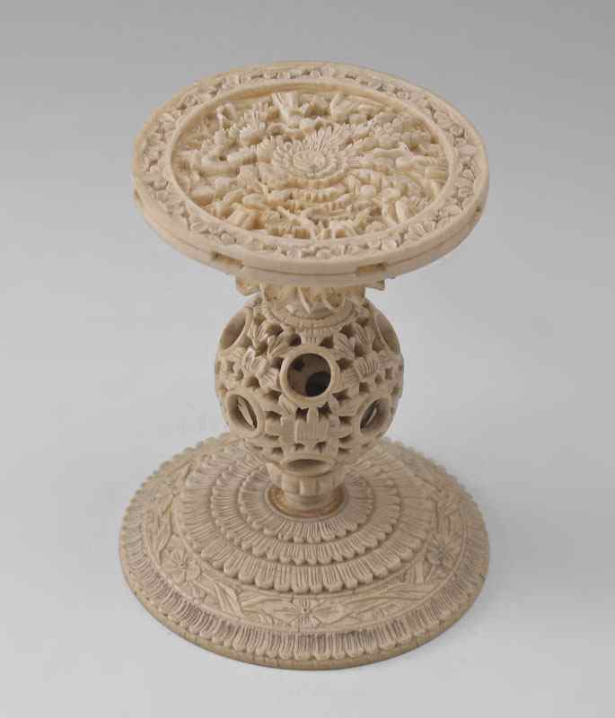 Appraisal: CARVED IVORY MYSTERY BALL STAND Intricate carved top featuring figures