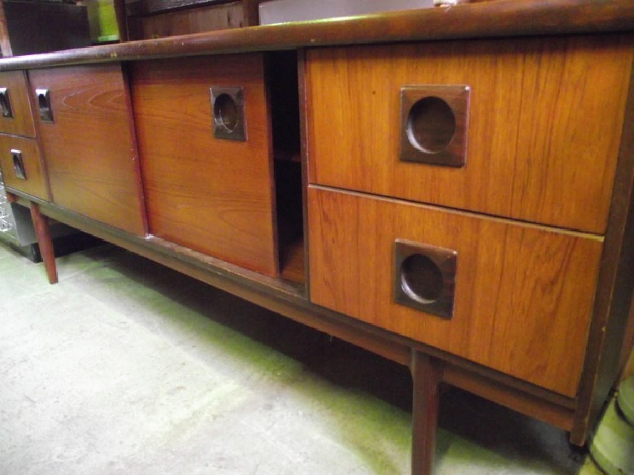 Appraisal: A mid th century long and low teak sideboard partially