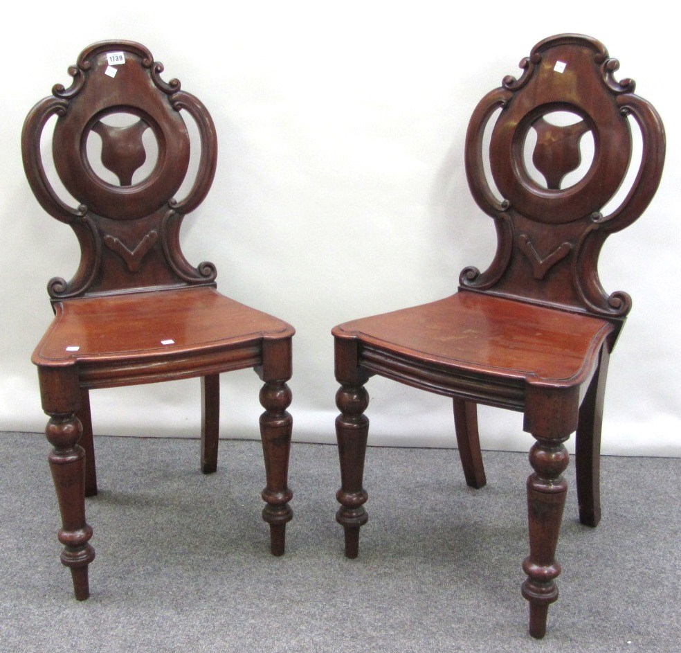 Appraisal: A pair of Victorian mahogany hall chairs with pierced armorial