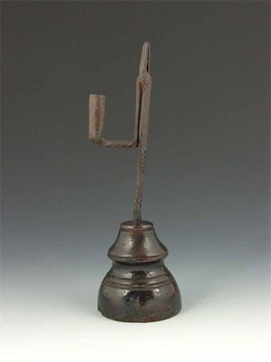 Appraisal: An th century wrought iron rush light with a turned