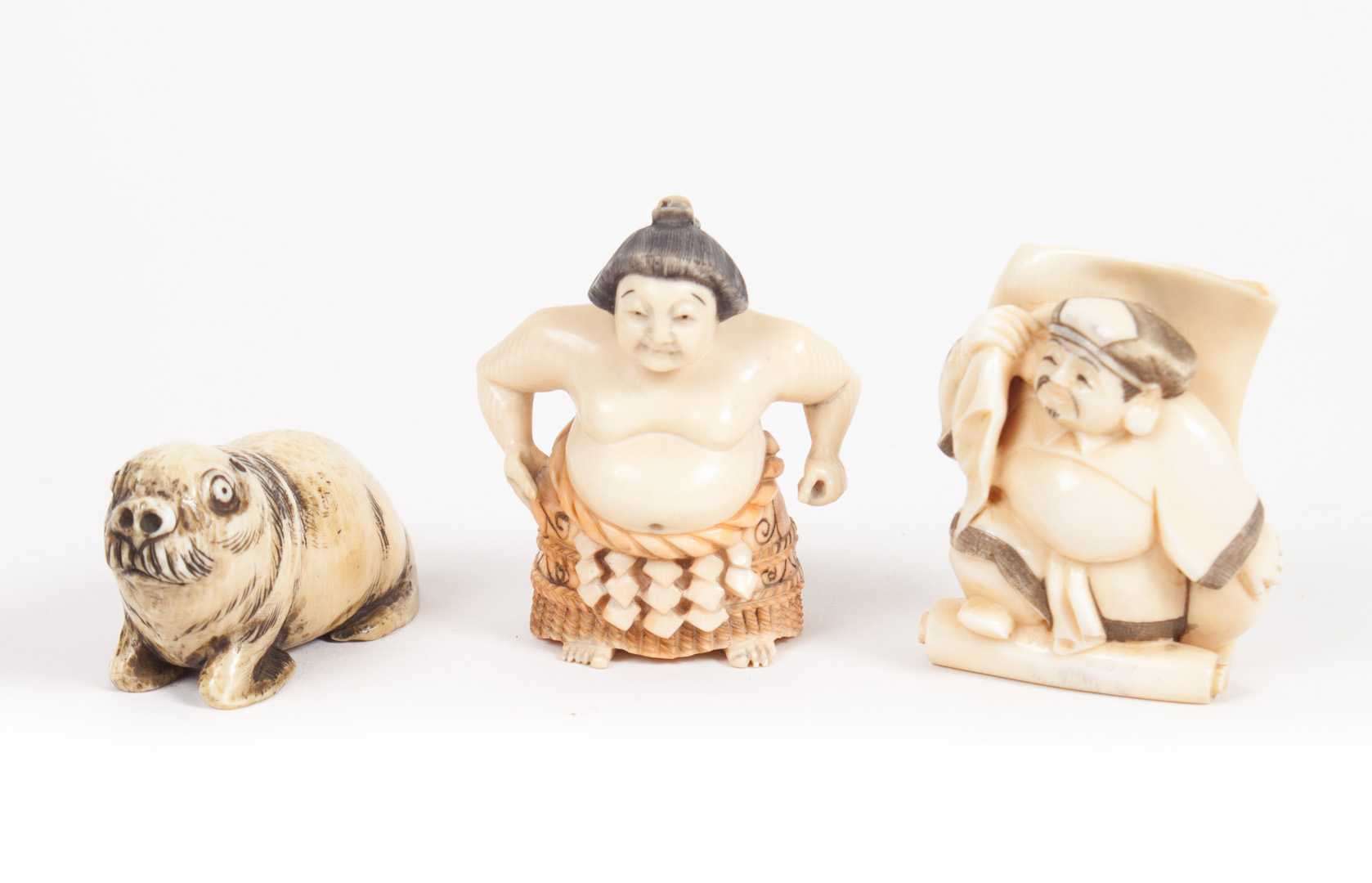 Appraisal: Three Japanese carved ivory netsukes all with ink highlights figures