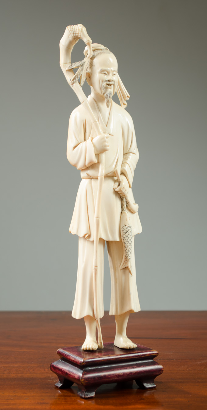 Appraisal: CHINESE CARVED IVORY FISHERMAN featuring a standing man with a