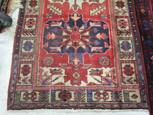 Appraisal: PERSIAN HERIZ RUNNER the red field featuring five geometric medallions