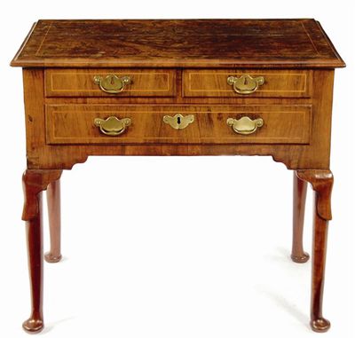 Appraisal: A walnut lowboy the quarter veneered moulded edge top above