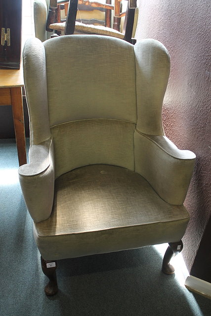 Appraisal: A GREEN UPHOLSTERED WINGBACK ARMCHAIR on short cabriole supports and