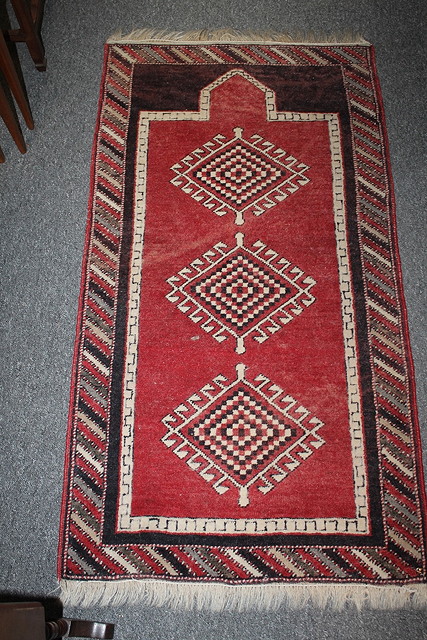 Appraisal: A SMALL TURKISH RED GROUND RUG with three medallions within