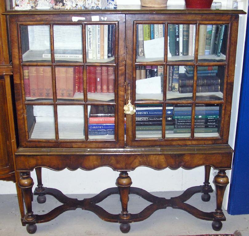 Appraisal: A walnut William Mary design glazed cabinet on stand with