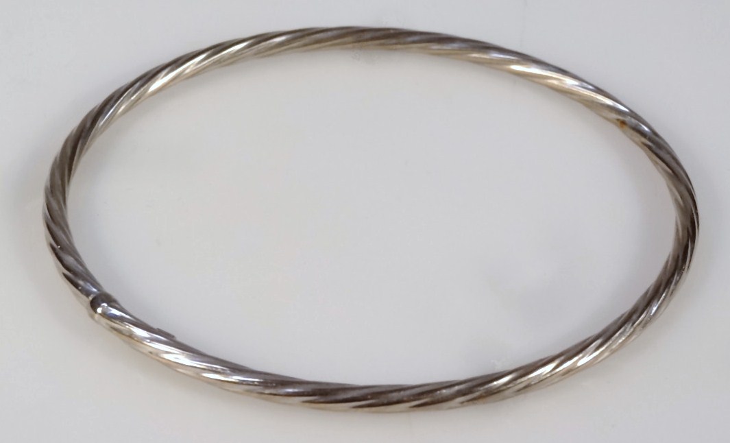 Appraisal: A twist bangle with a compressed body white metal marked