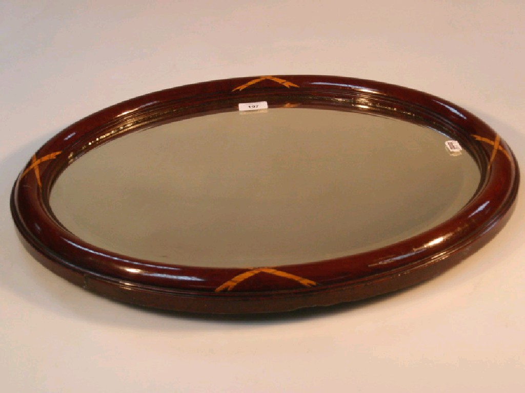 Appraisal: A bevelled oval wall mirror in simulated mahogany frame