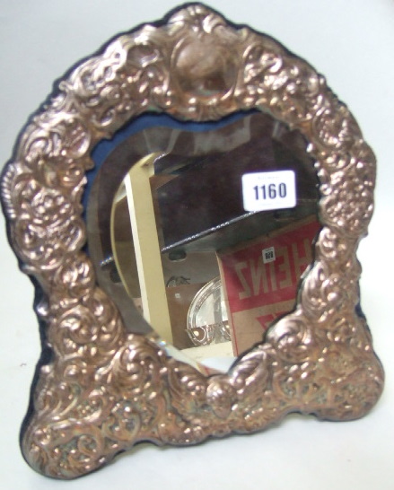 Appraisal: A modern embossed silver cartouche shaped easel mirror with bevelled