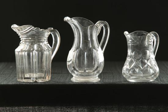 Appraisal: THREE CLEAR CUT MILK PITCHERS Pittsburgh th century Flint Glass