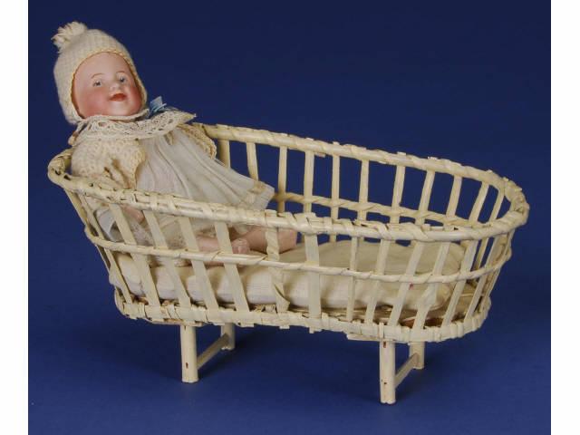 Appraisal: Laughing Heubach Baby with Wicker Cradle Germany ca bisque socket