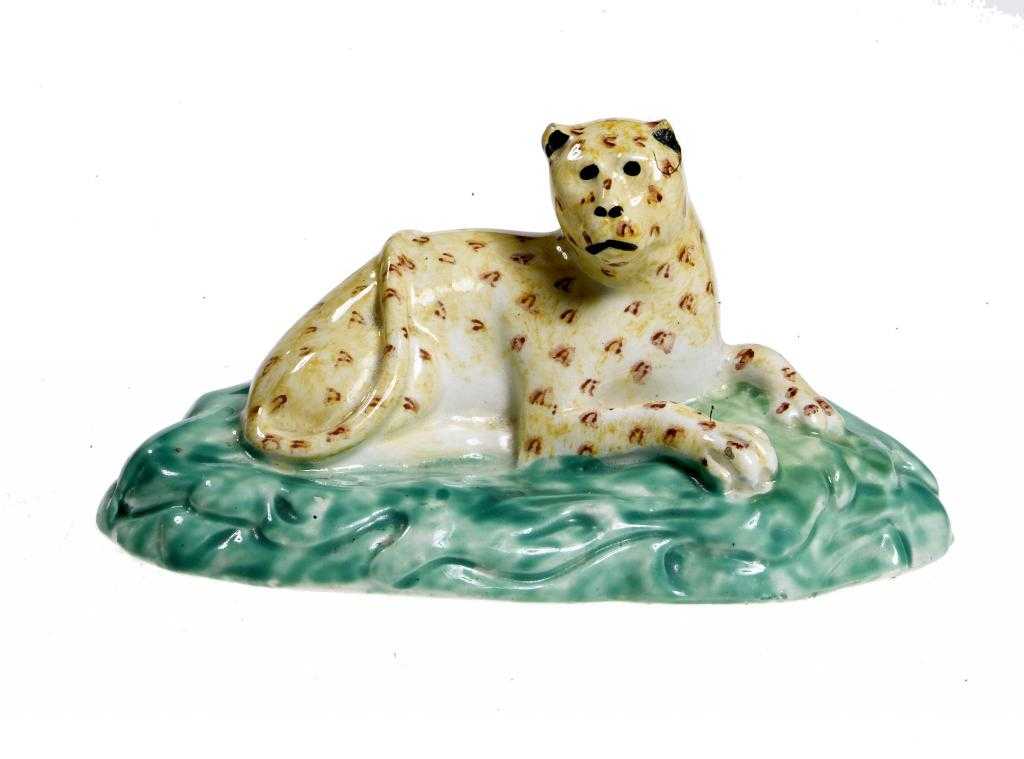 Appraisal: A CREAMWARE MODEL OF A LEOPARD lying on a rocky