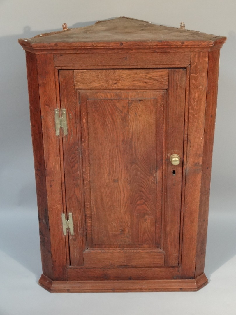 Appraisal: An early thC elm hanging corner cupboard the panelled door