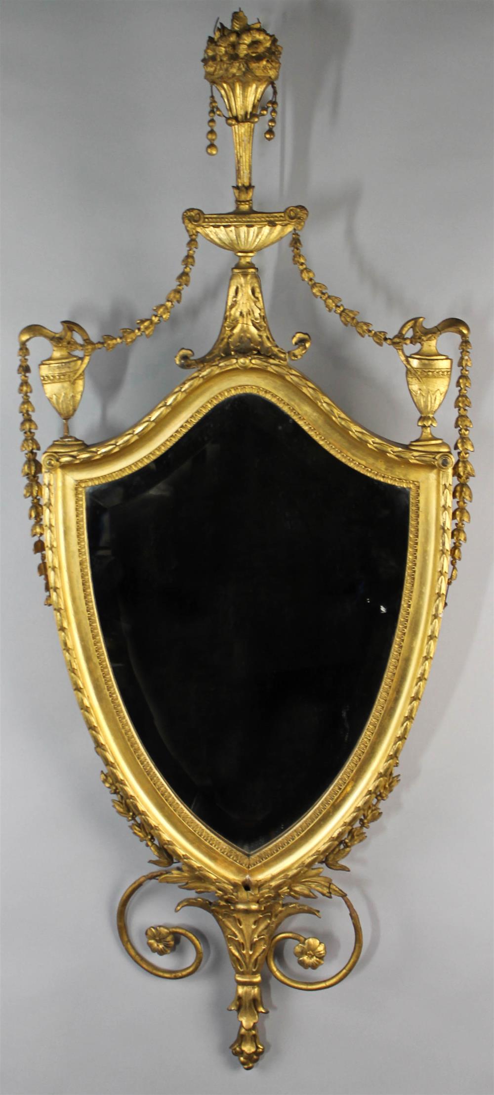 Appraisal: NEOCLASSICAL GILT MIRROR the shield shaped plate enclosed by garland