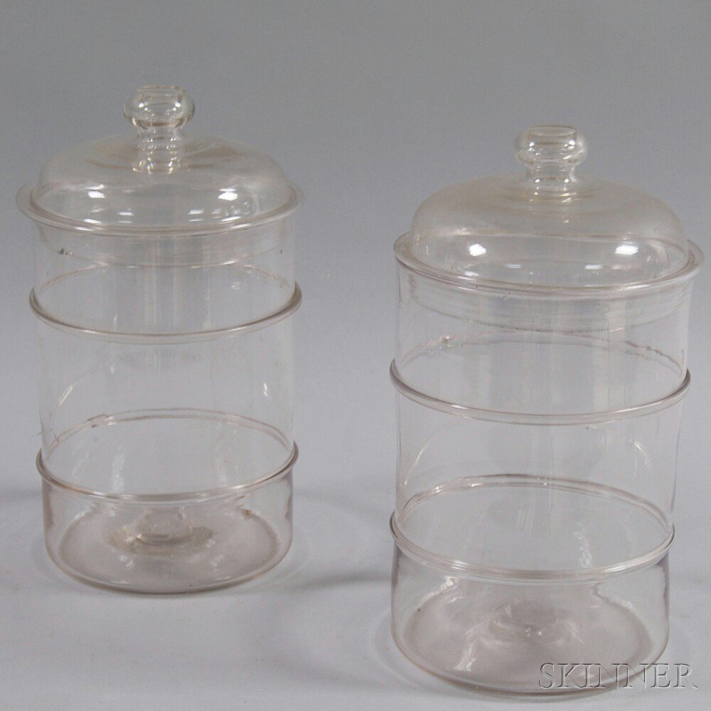 Appraisal: Pair of Colorless Glass Covered Jars th century the body