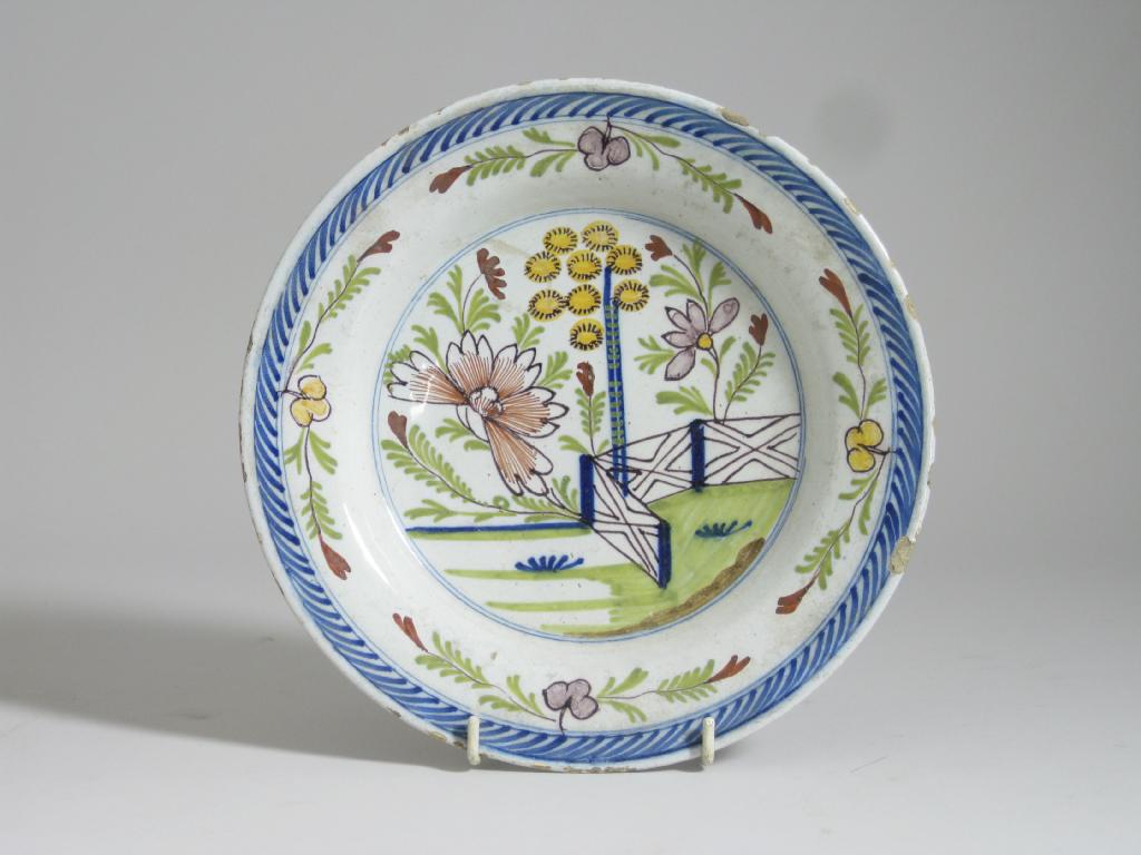 Appraisal: A polychrome Delft Plate painted landscape with fence and flowers