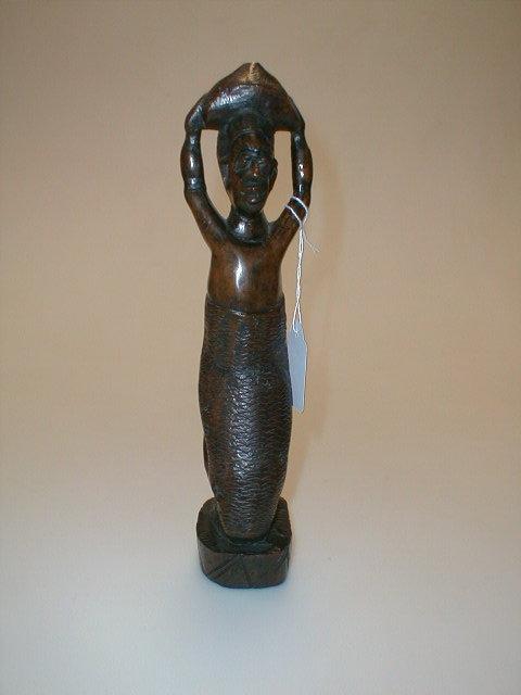 Appraisal: An African hardwood figure carved as a native kneeling holding