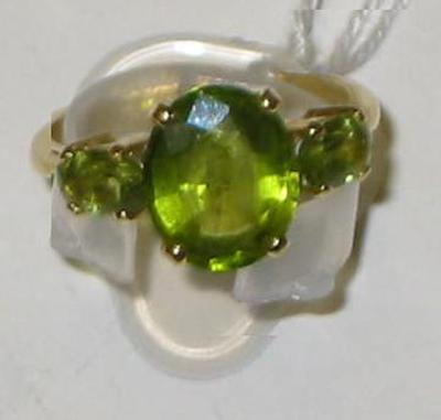 Appraisal: A THREE STONE PERIDOT RING the central oval faceted stone