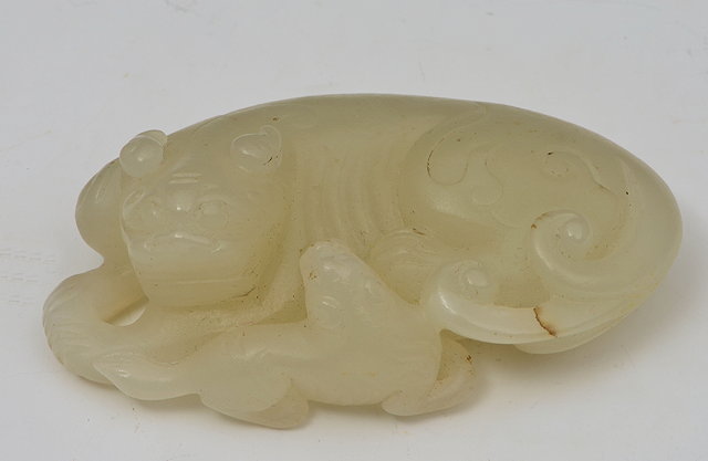 Appraisal: A CHINESE WHITE JADE PEBBLE carved as a recumbent mythological