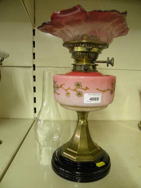 Appraisal: A Victorian oil lamp with a cranberry tinted shade decorated