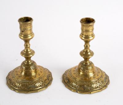 Appraisal: A pair of engraved brass candlesticks on skirt bases cm