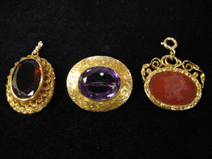 Appraisal: Three gold necklace charms Two oval-shaped with large amethyst and