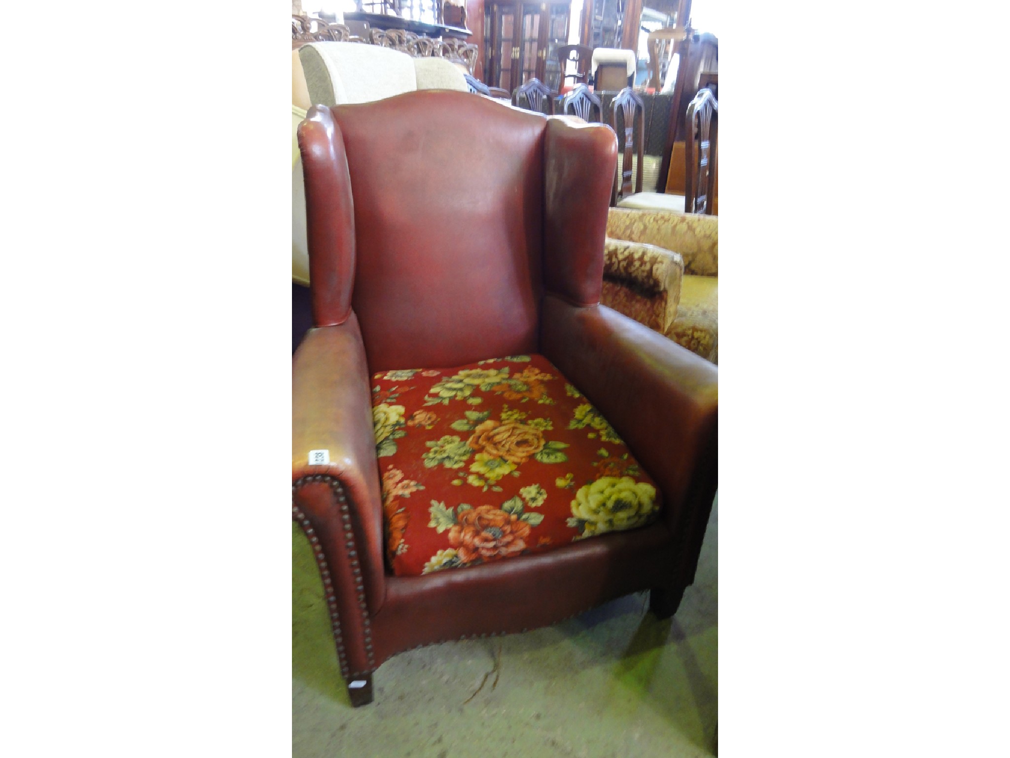 Appraisal: A vintage low wing armchair with shaped outline burgundy coloured