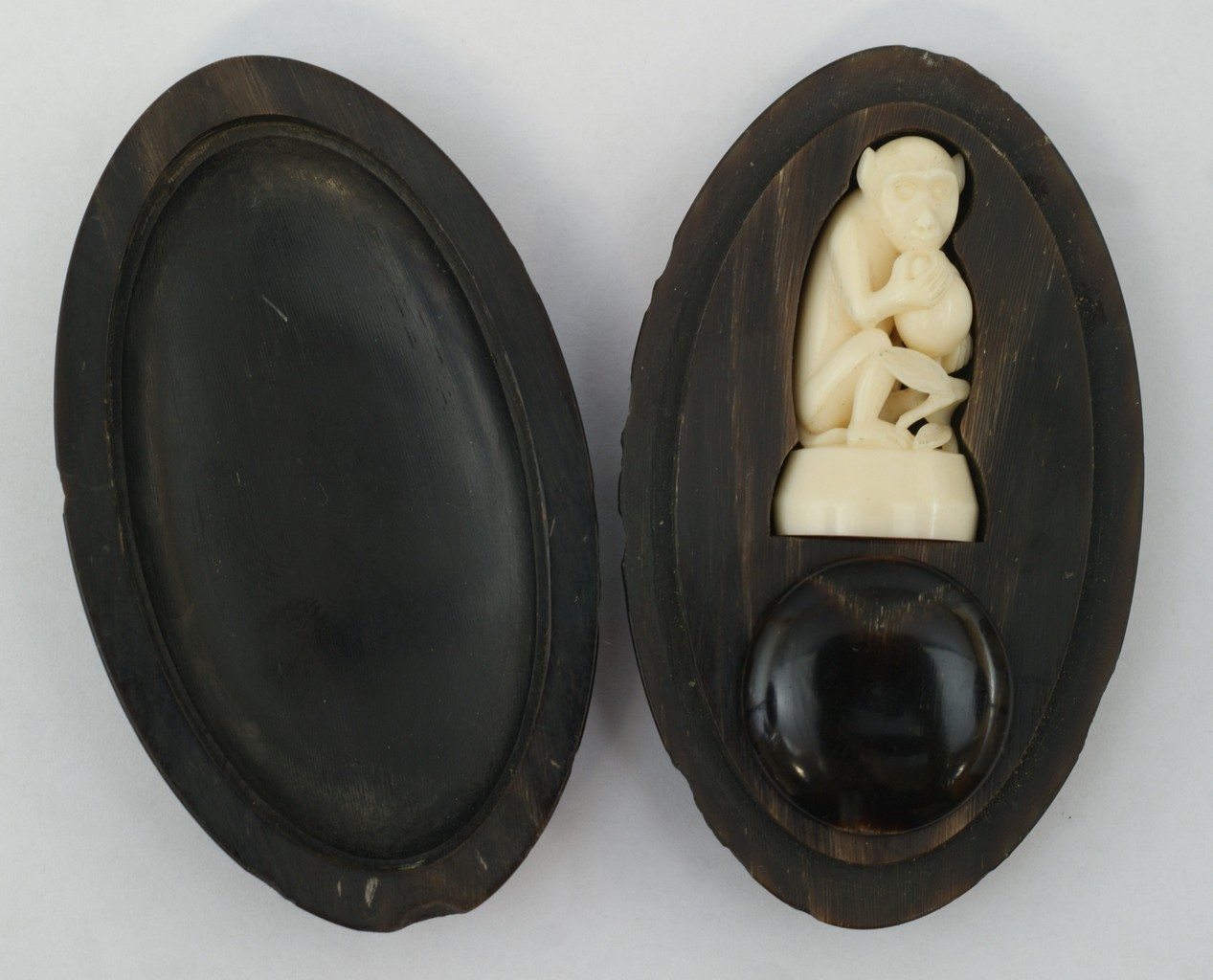 Appraisal: Carved ivory monkey with seal to base in carved horn