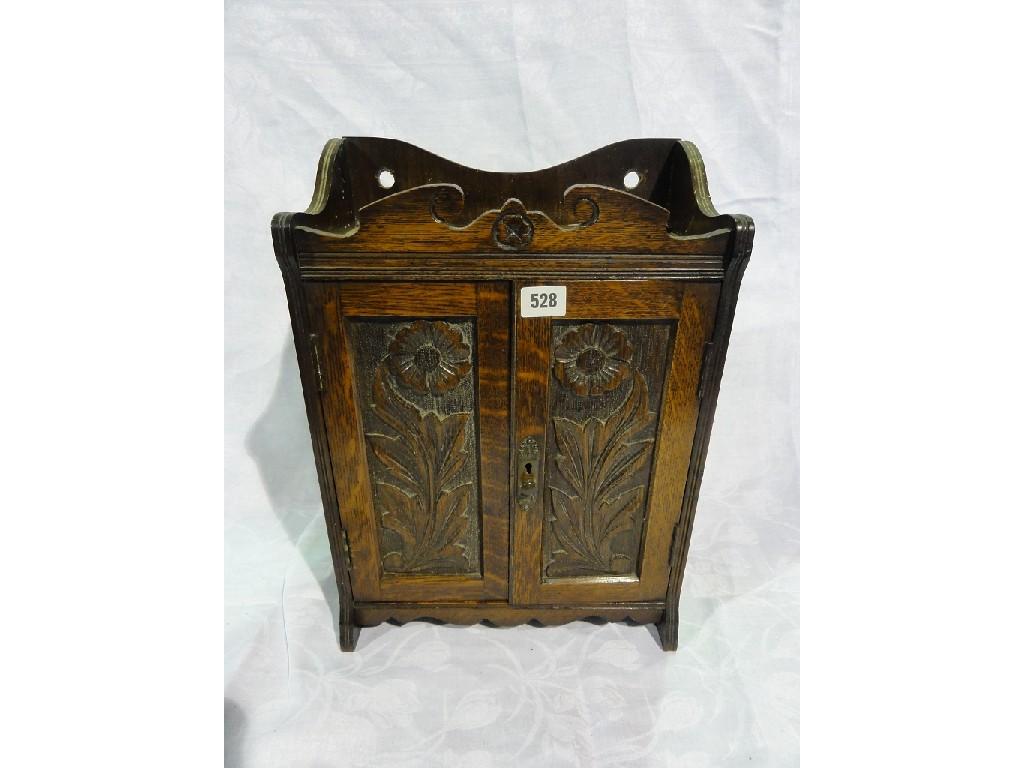 Appraisal: An oak smokers companion with flower carved panel doors opening