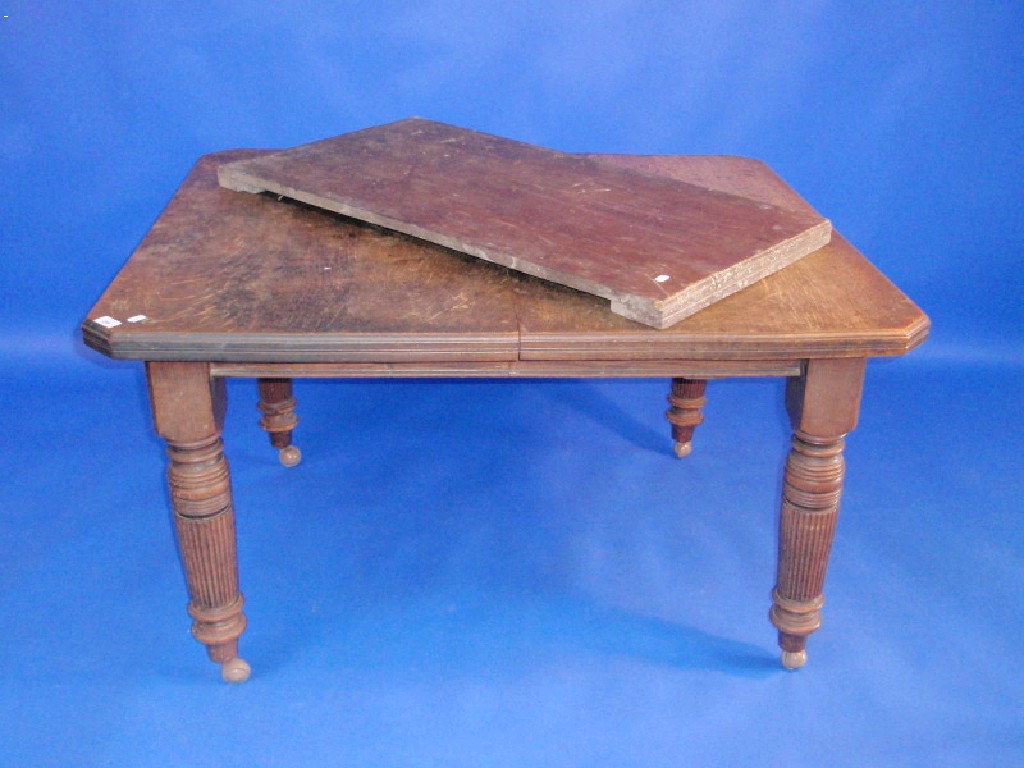 Appraisal: An Edwardian oak dining table with moulded and canted top