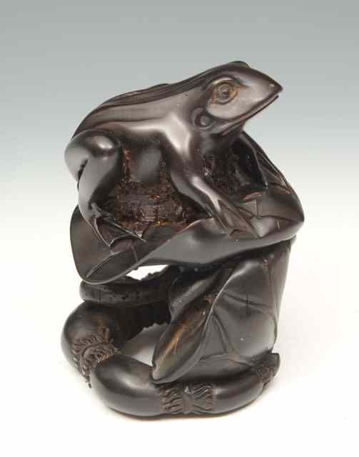 Appraisal: A CARVED HARDWOOD TOAD seated on a lily pad high