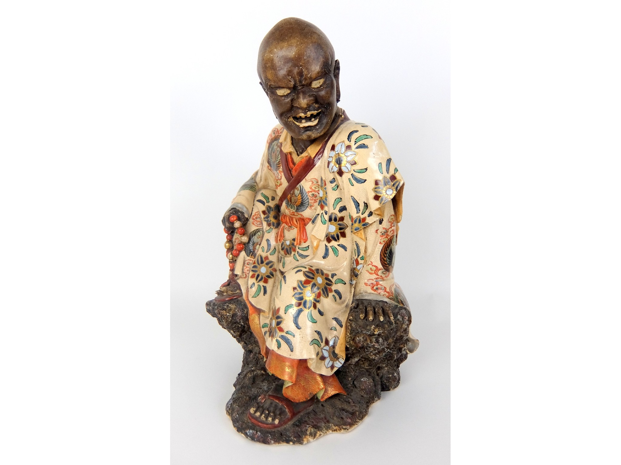 Appraisal: A Japanese pottery figure of a monkseated in prayer and